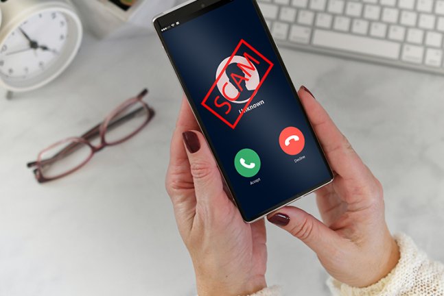 Bild von zwei Händen die ein Smartphone halten und auf dem Display steht SCAM
