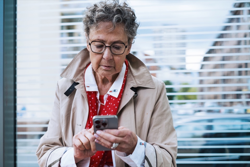 Seniorin liest aufmerksam eine Nachricht auf ihrem Smartphone