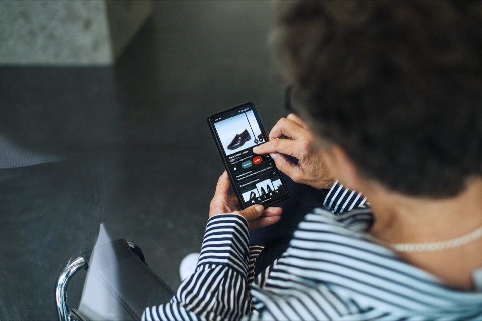 Ältere Frau tippt auf ihrem Smartphone auf die Produktseite eines Online-Shops