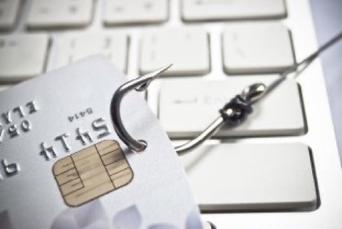 Angelhaken durchbohrt eine Bankkarte auf einer Tastatur als Phishing-Symbol