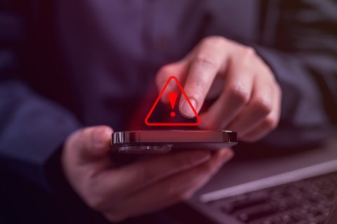 Warndreieck leuchtet &uuml;ber einem Smartphone in der Hand