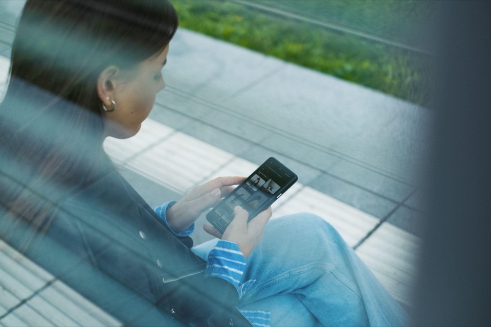 Junge Frau schaut konzentriert auf ihr Smartphone im Freien