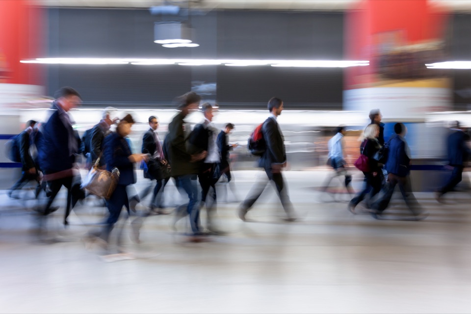 Bewegungsunscharfe Menschenmenge, die durch eine Bahnhofshalle strömt