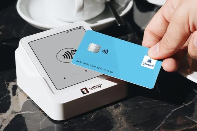 Girocard wird kontaktlos an einem SumUp-Zahlterminal gehalten