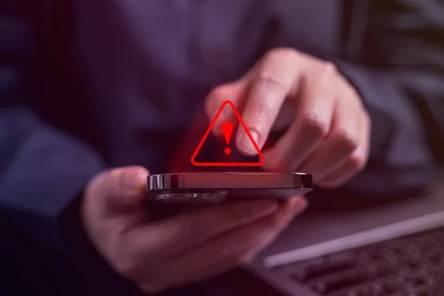 Warndreieck leuchtet über einem Smartphone in der Hand